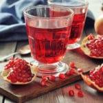 24051807 – ripe pomegranate fruit and glass of juice on wooden background